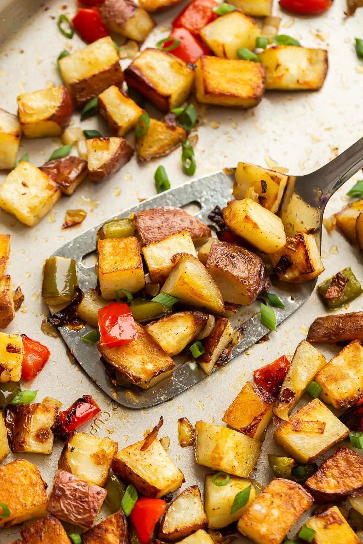 metal ladle scooping breakfast potatoes from pan.