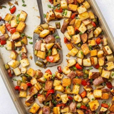 overhead image of breakfast potatoes on a sheet pan with spatula.