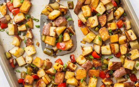 overhead image of breakfast potatoes on a sheet pan with spatula.