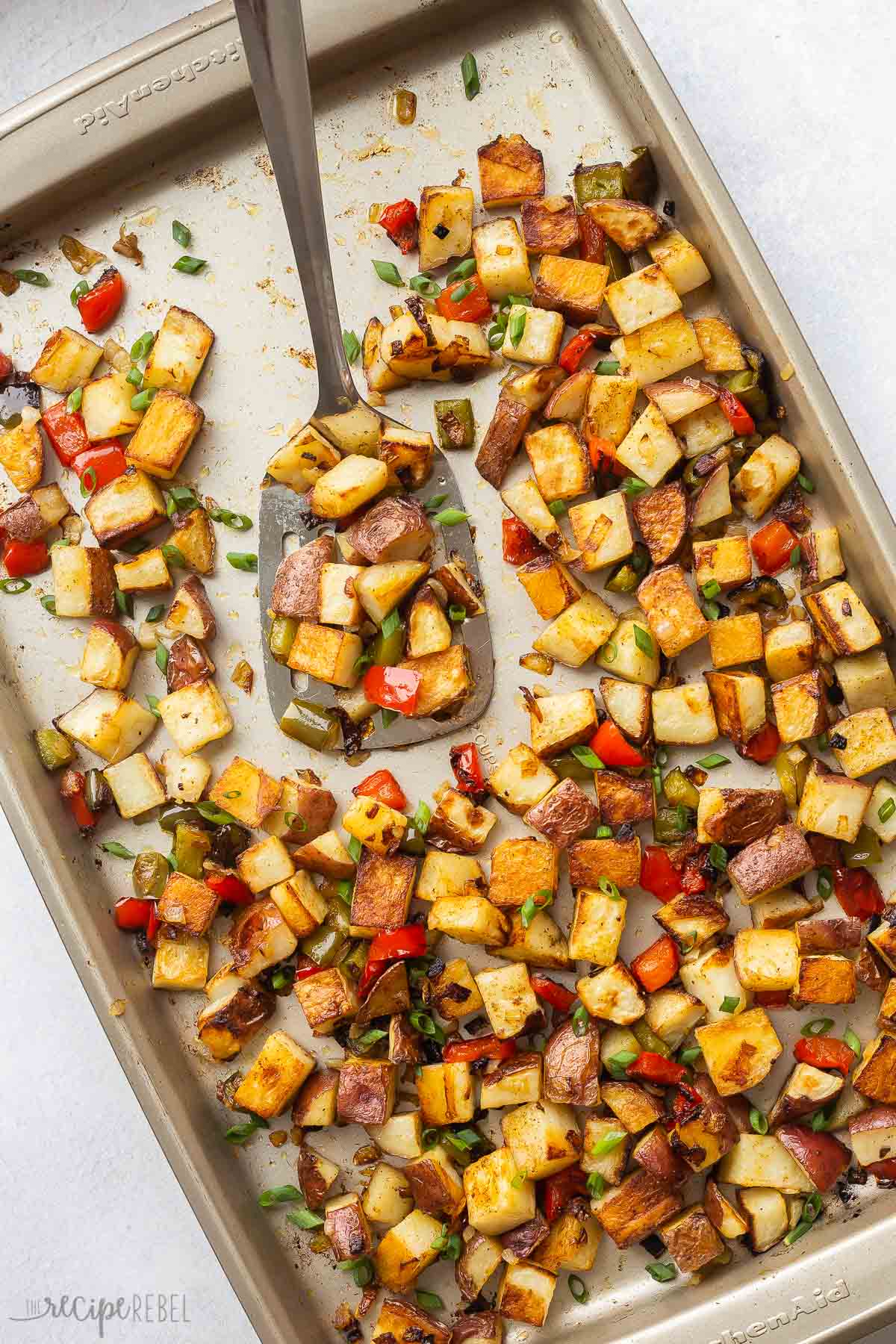 overhead image of breakfast potatoes on a sheet pan with spatula.