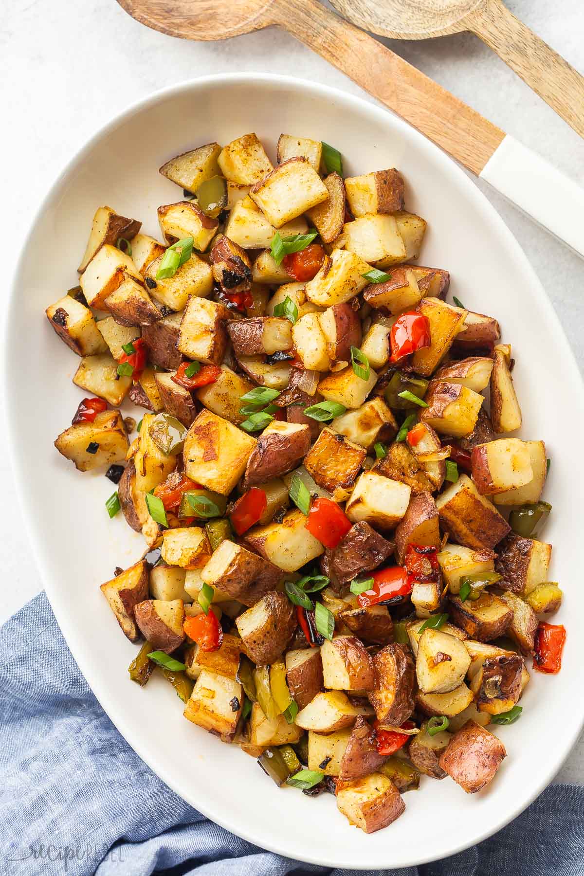 roasted breakfast potatoes with peppers on a white serving platter.