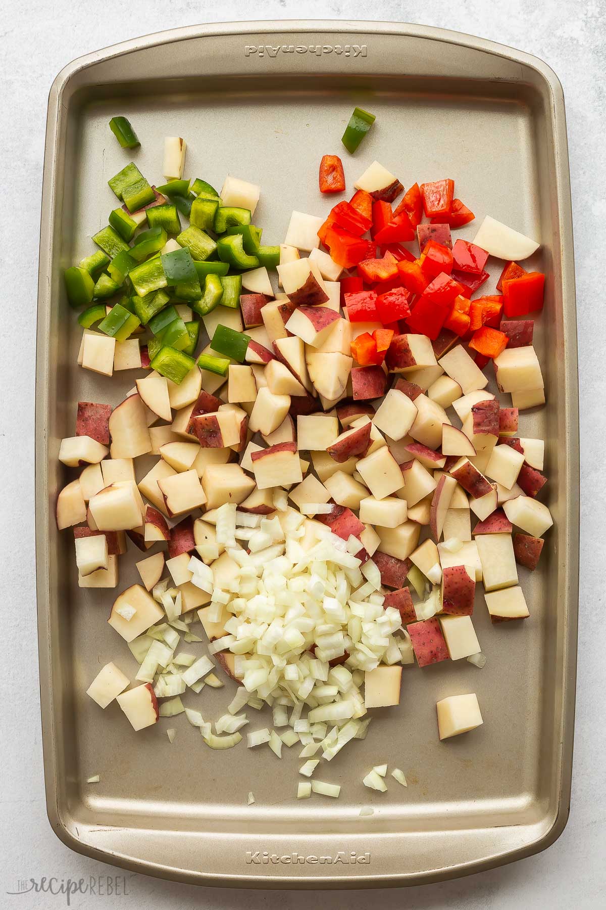 potatoes peppers and onions on a sheet pan.