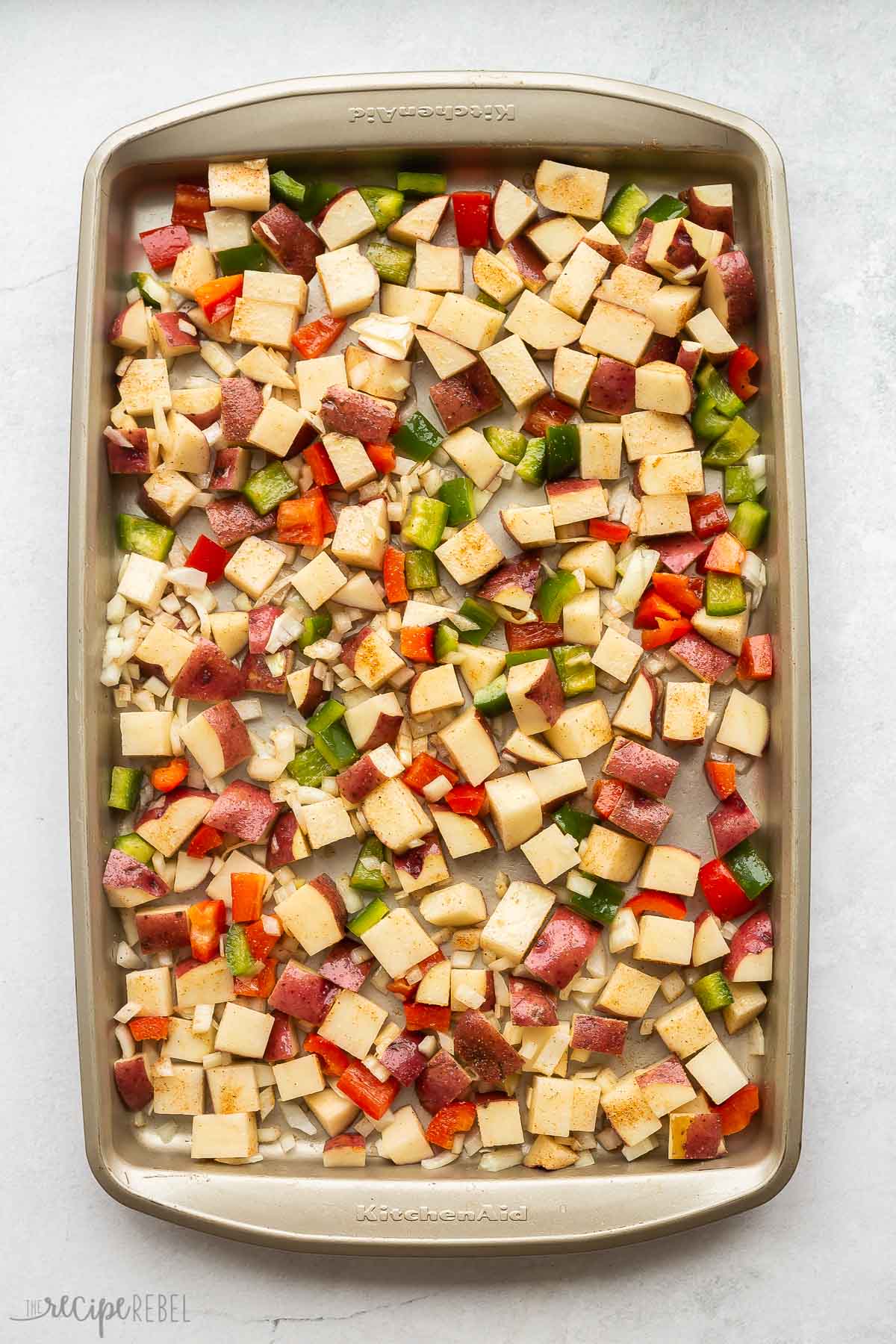 ingredients for breakfast potatoes stirred together on pan.