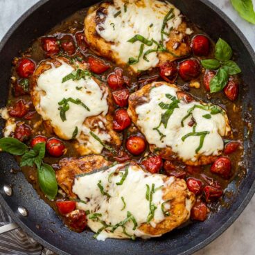 overhead image of caprese chicken in black skillet on marble.