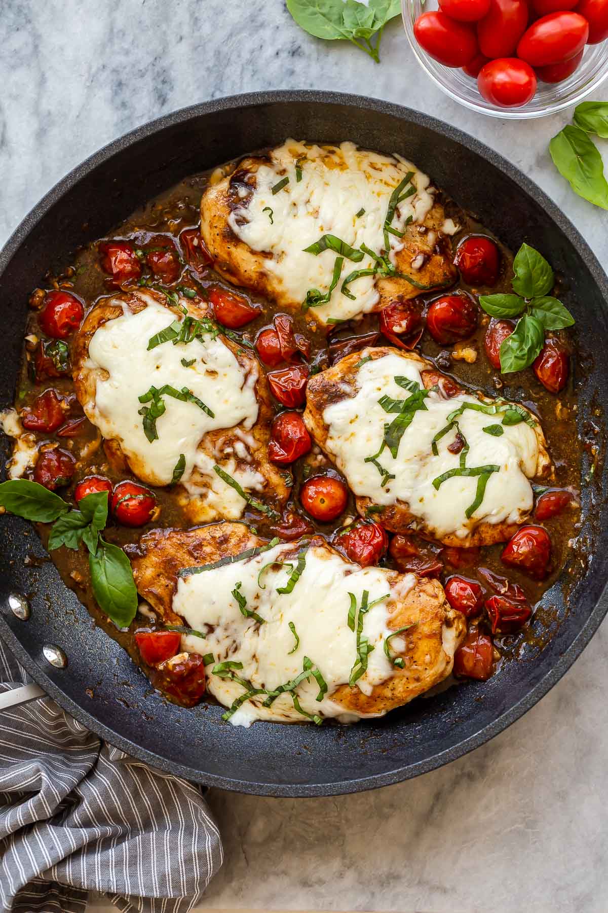 overhead image of caprese chicken in black skillet on marble.