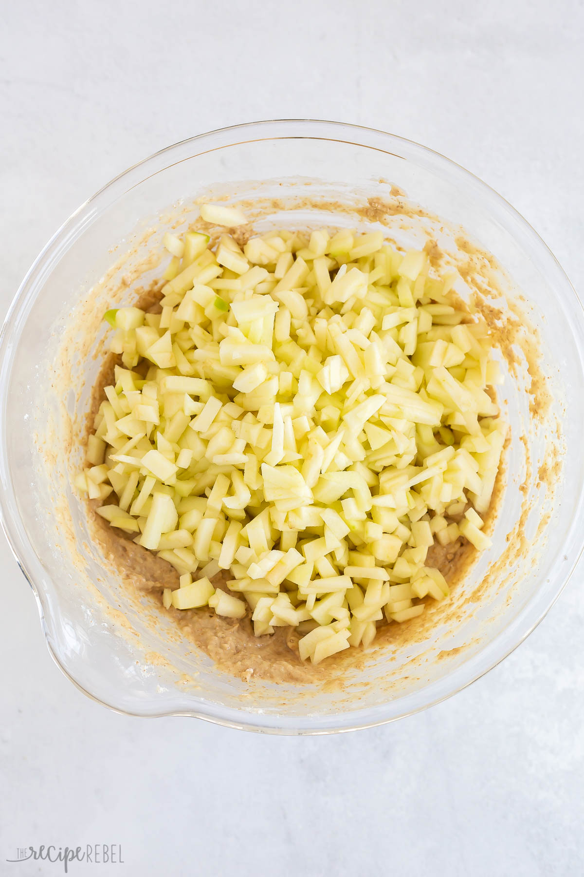 chopped apples added to muffin batter in bowl.