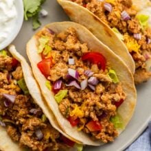 close up image of ground turkey tacos with tomatoes and red onion.