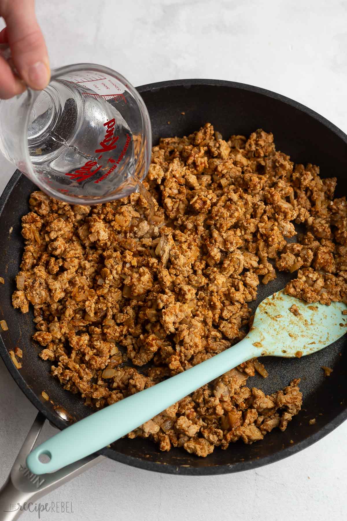 water being added to turkey tacos in skillet.