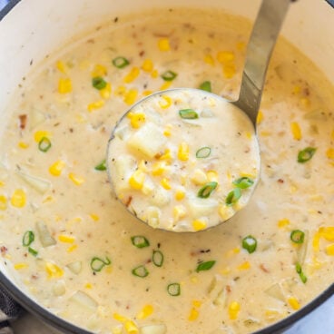 metal ladle scooping potato corn chowder from dutch oven.