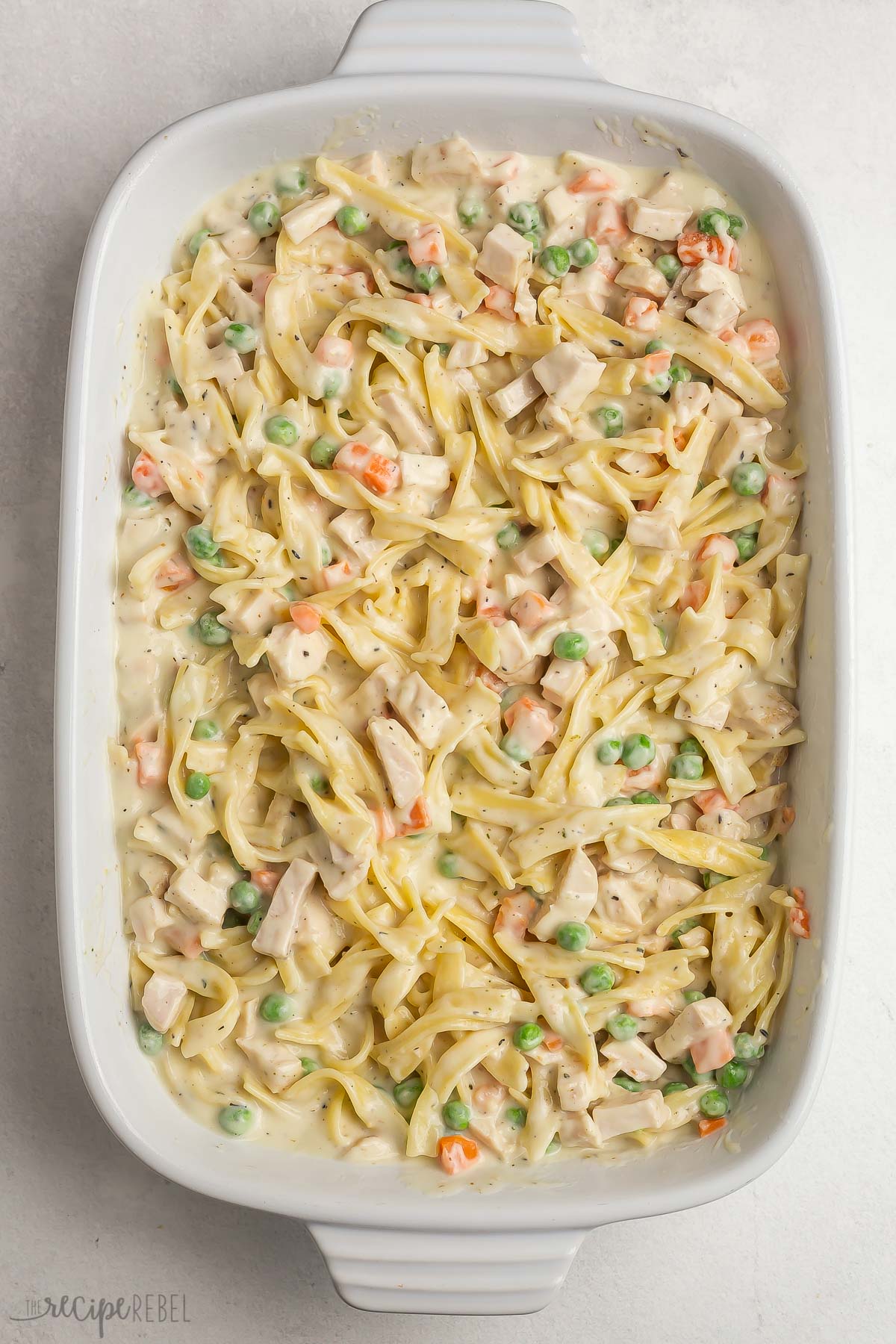 noodles with creamy sauce chicken and vegetables in white baking dish.