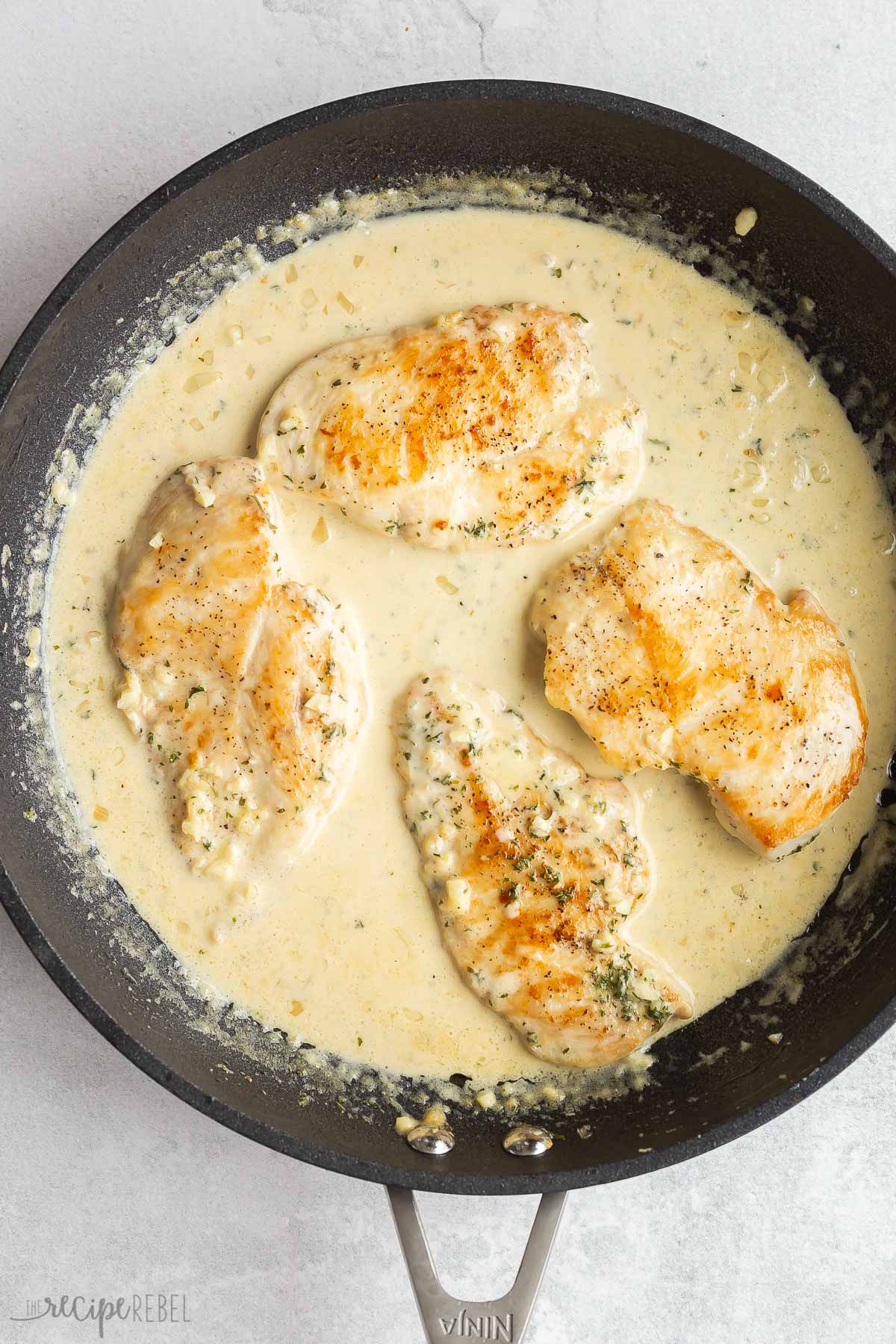 chicken with creamy sauce in skillet.