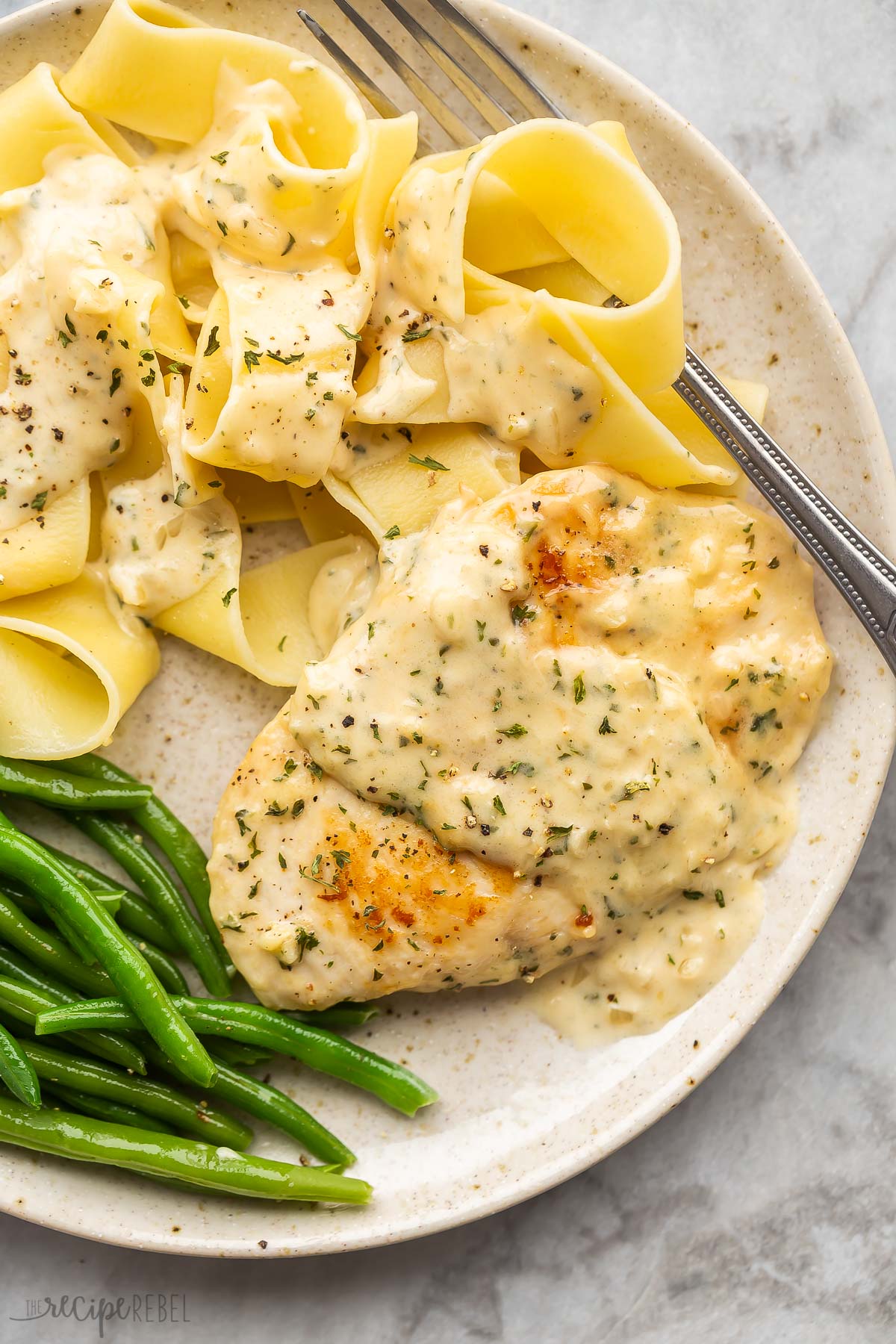 chicken in garlic sauce on plate with noodles and green beans.