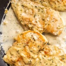 close up image of four creamy garlic chicken breasts in black skillet.