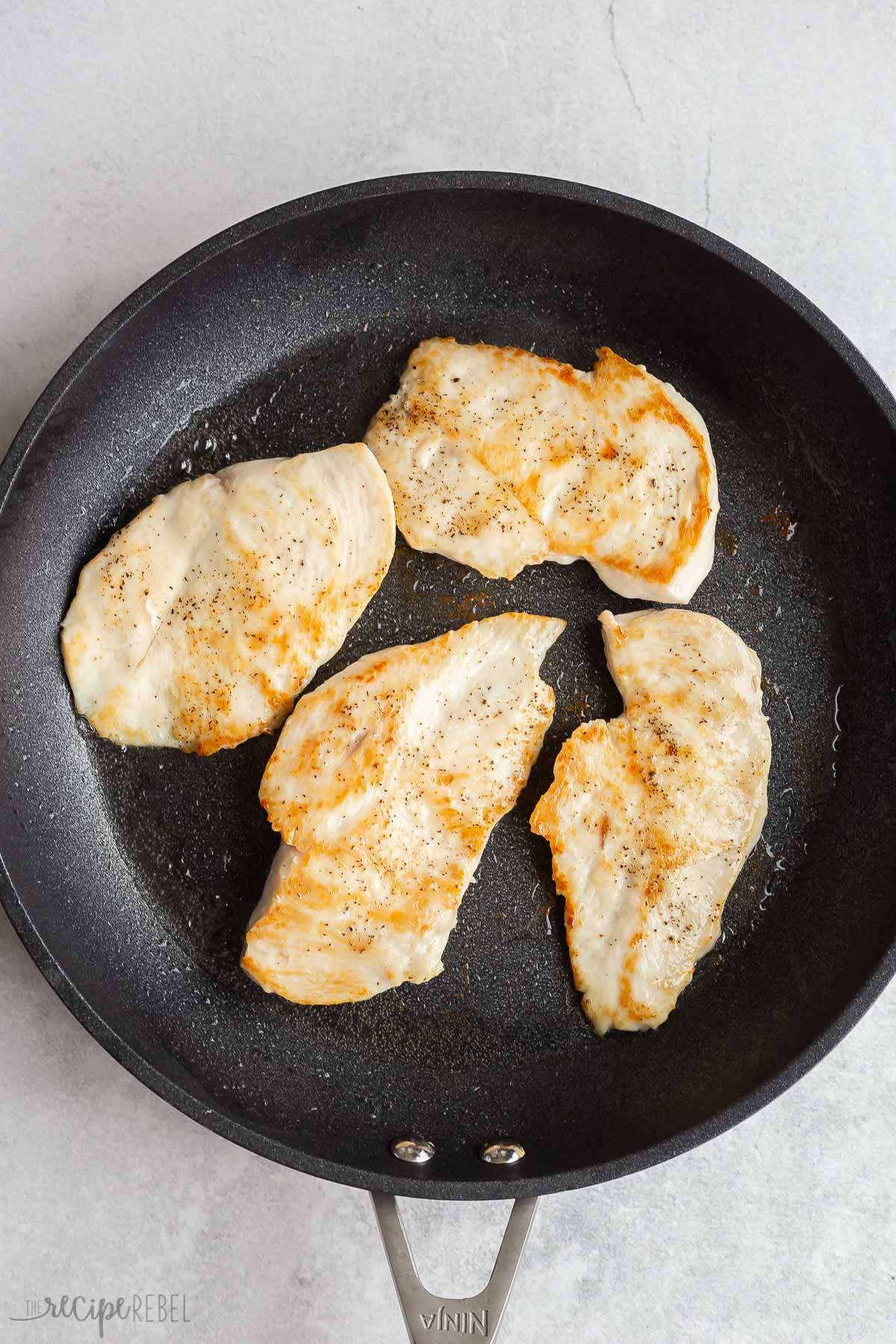 browned chicken breasts in black skillet.