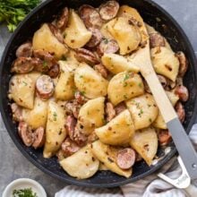 overhead image of perogies and sausage in black skillet on grey background.