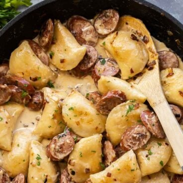 pinterest image for perogies and sausage with title over red background.