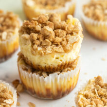 two apple crisp cheesecakes stacked with more in the background.