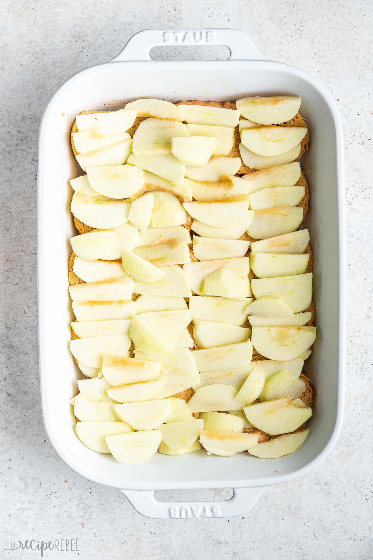 sliced apples layered over bread in baking dish.