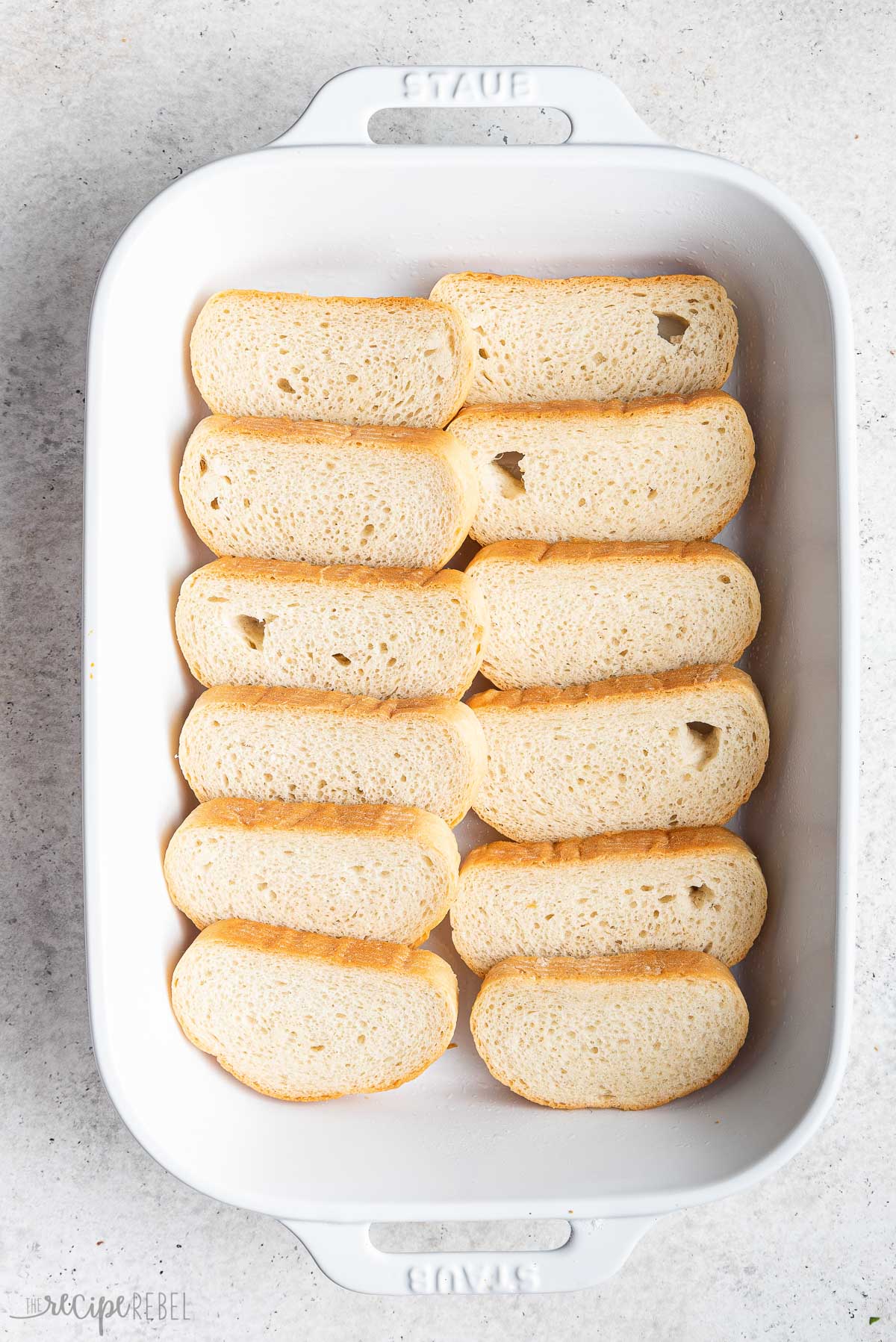 slices of french bread in white baking dish.