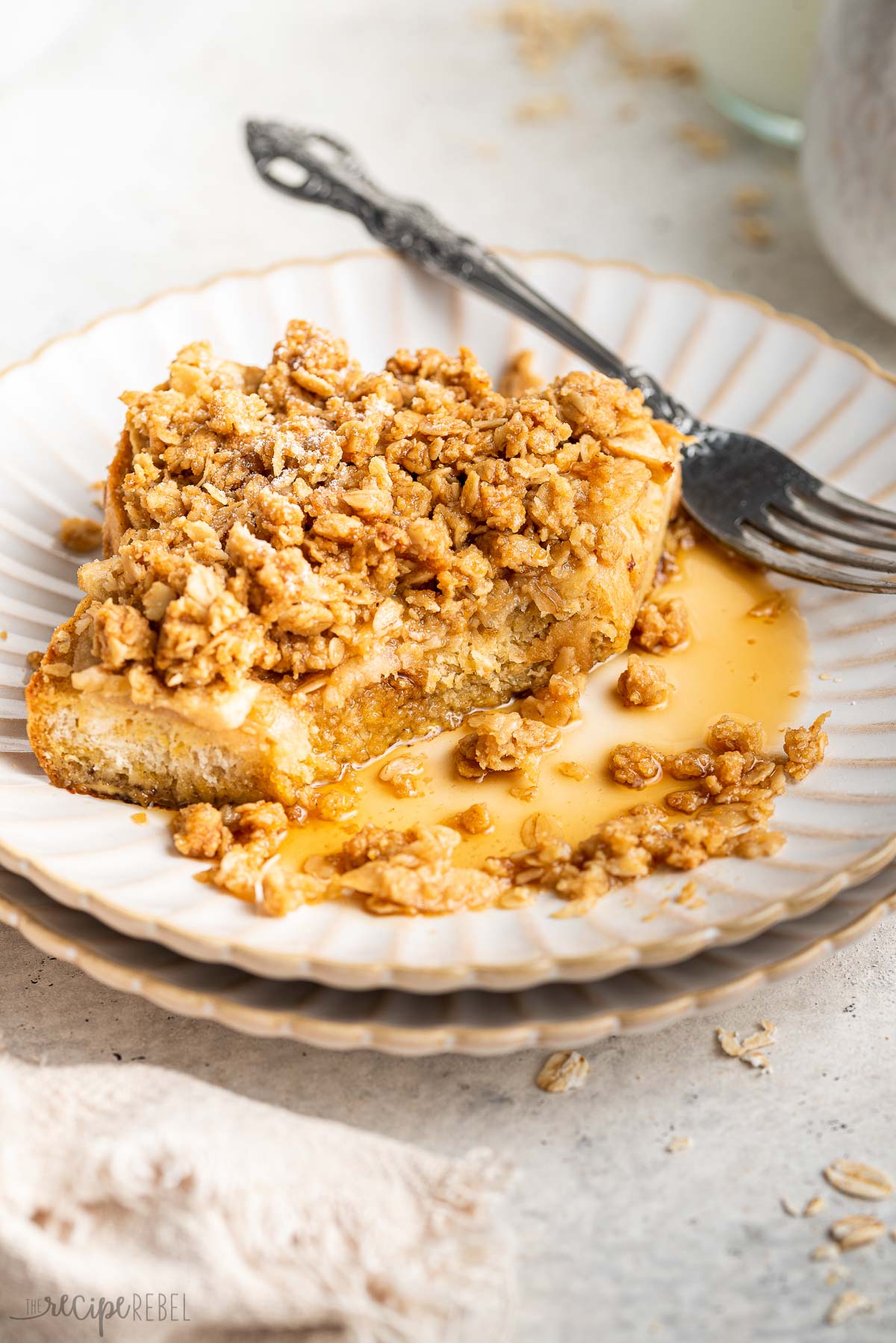 piece of apple french toast bake on white plate with fork and syrup.