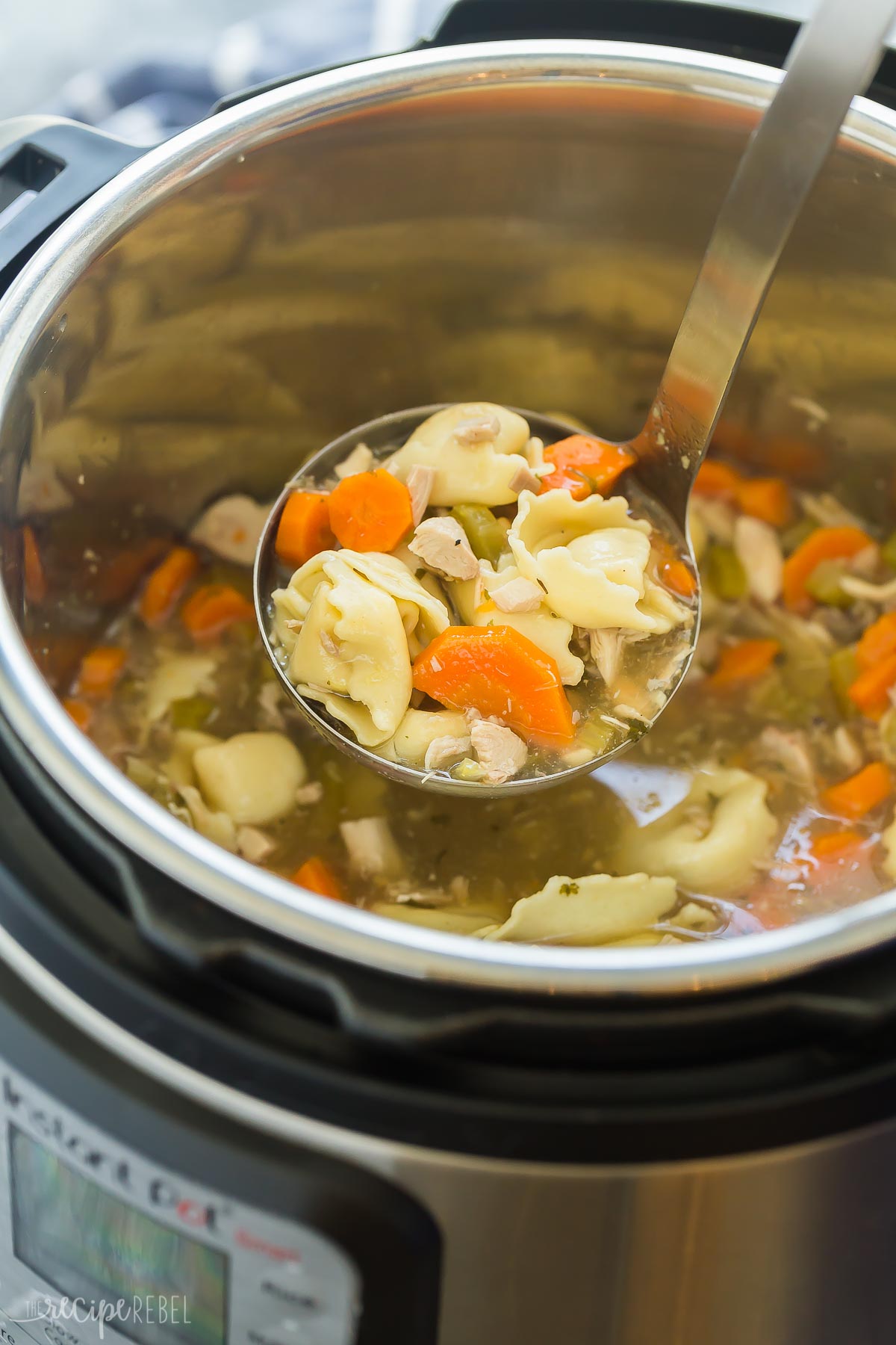 metal ladle scooping chicken tortellini soup out of instant pot.