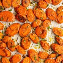 overhead image of roasted sliced carrots on parchment lined baking sheet.