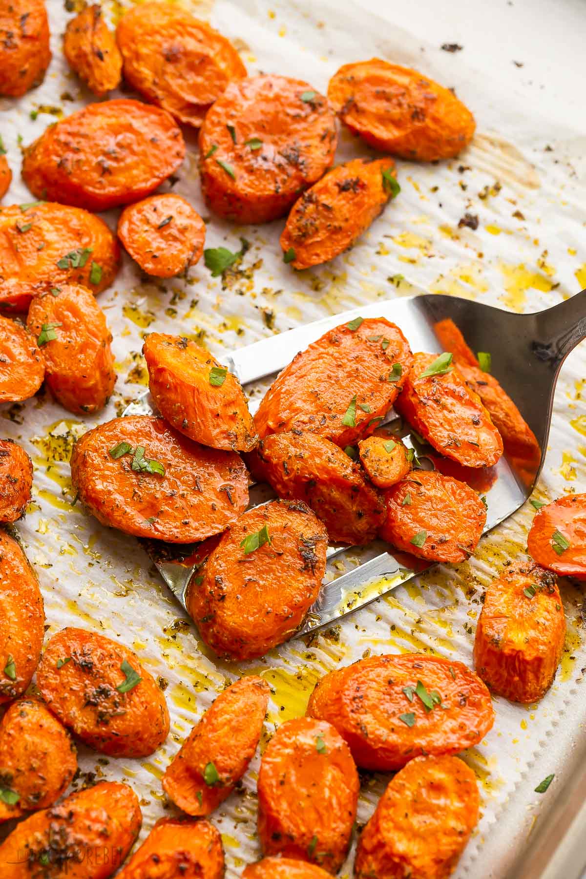 metal ladle scooping roasted carrots from pan.