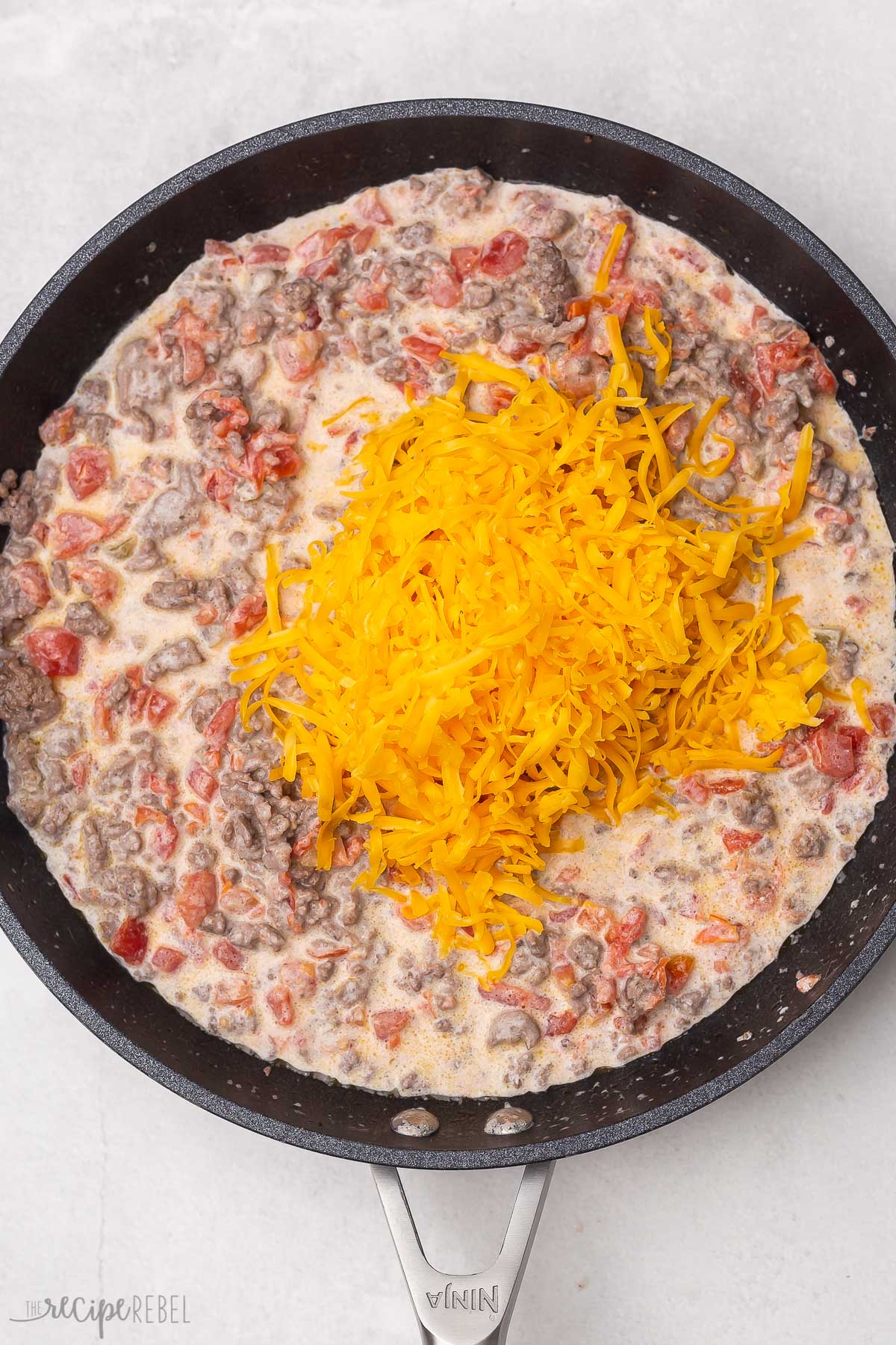 shredded cheddar cheese added to dip in skillet.