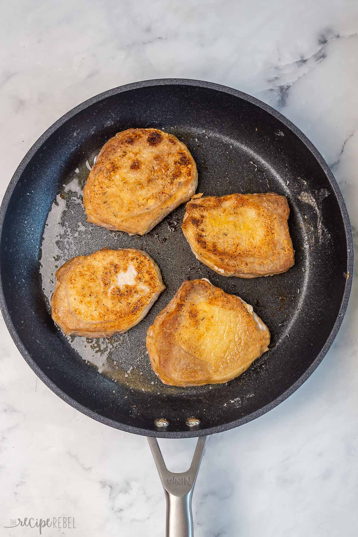 four boneless pork chops in pan after browning.