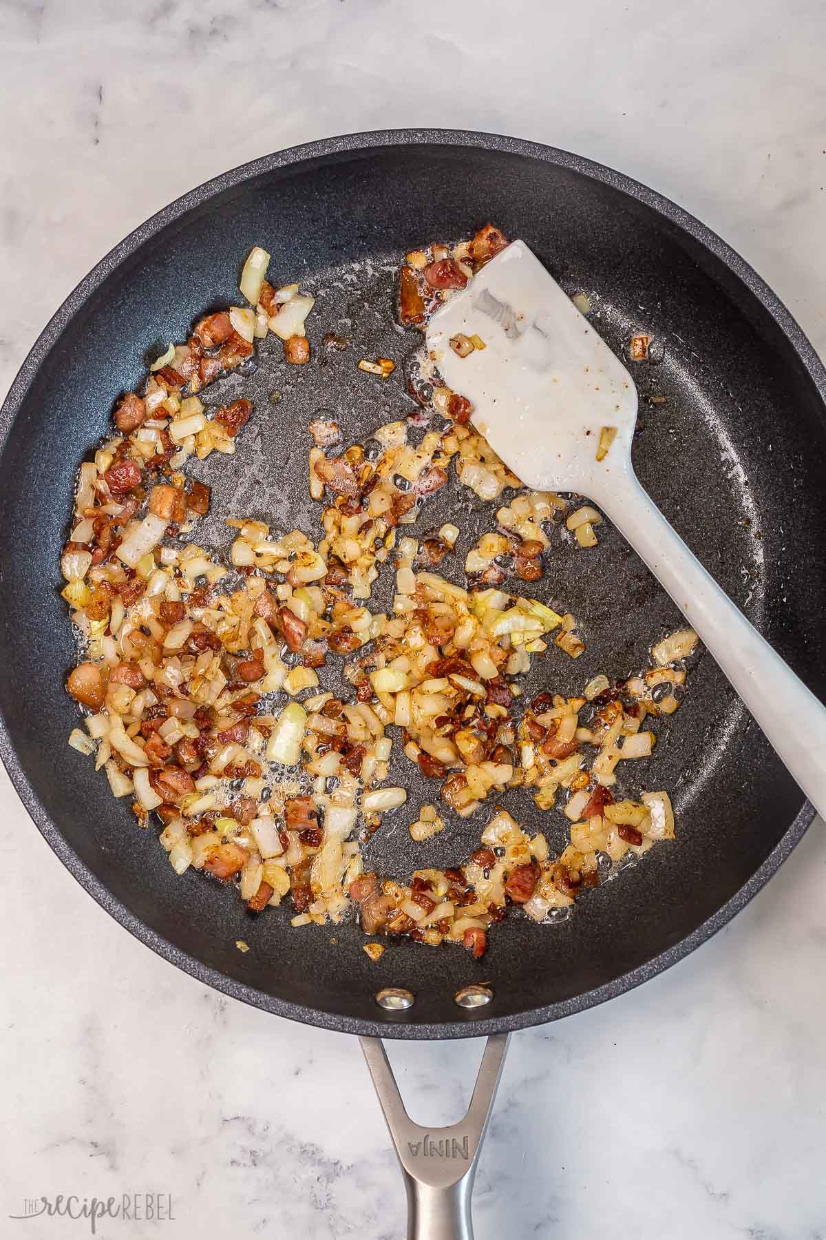 bacon and onions cooking in large black skillet.