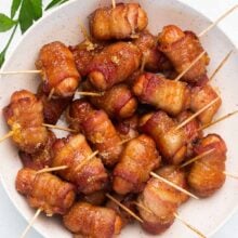 overhead image of bacon wrapped smokies in white bowl with toothpicks in.