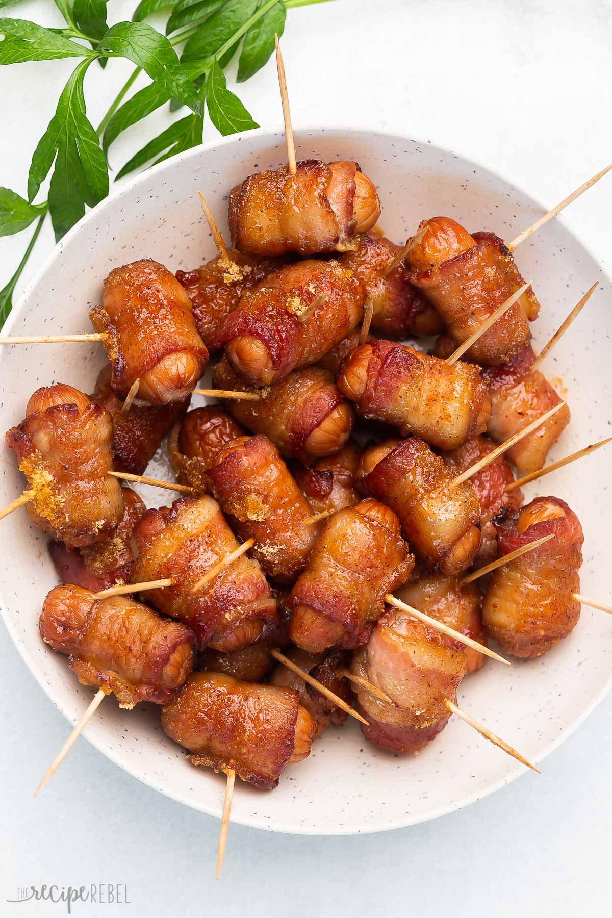 overhead image of bacon wrapped smokies in white bowl with toothpicks in.