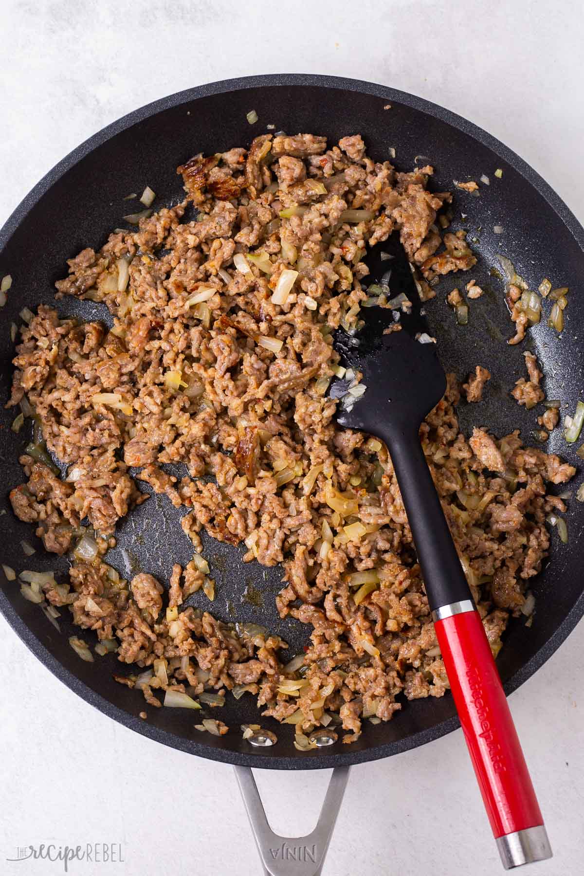 crumbled sausage cooked in black skillet.