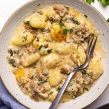backed gnocchi with sausage and creamy sauce in a bowl with a fork.