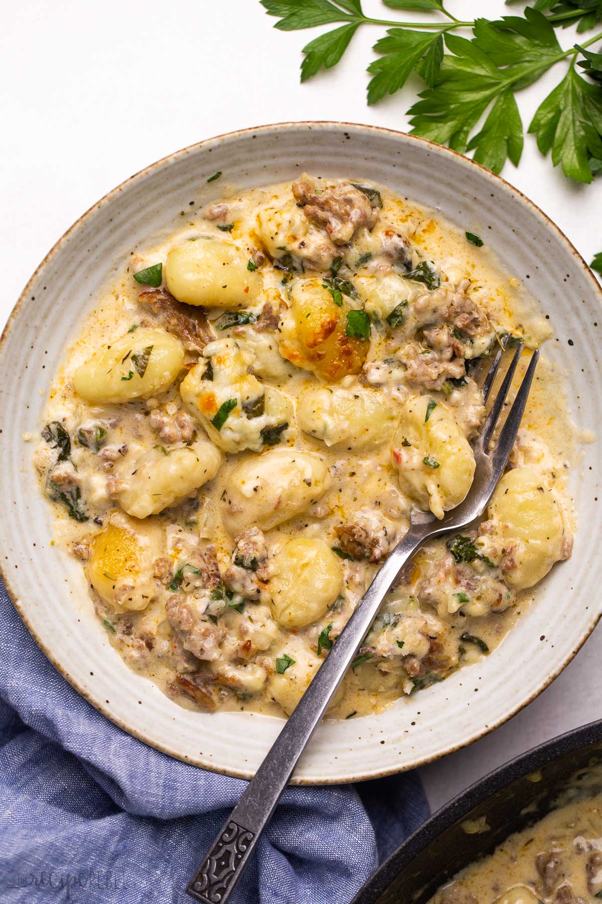 backed gnocchi with sausage and creamy sauce in a bowl with a fork.