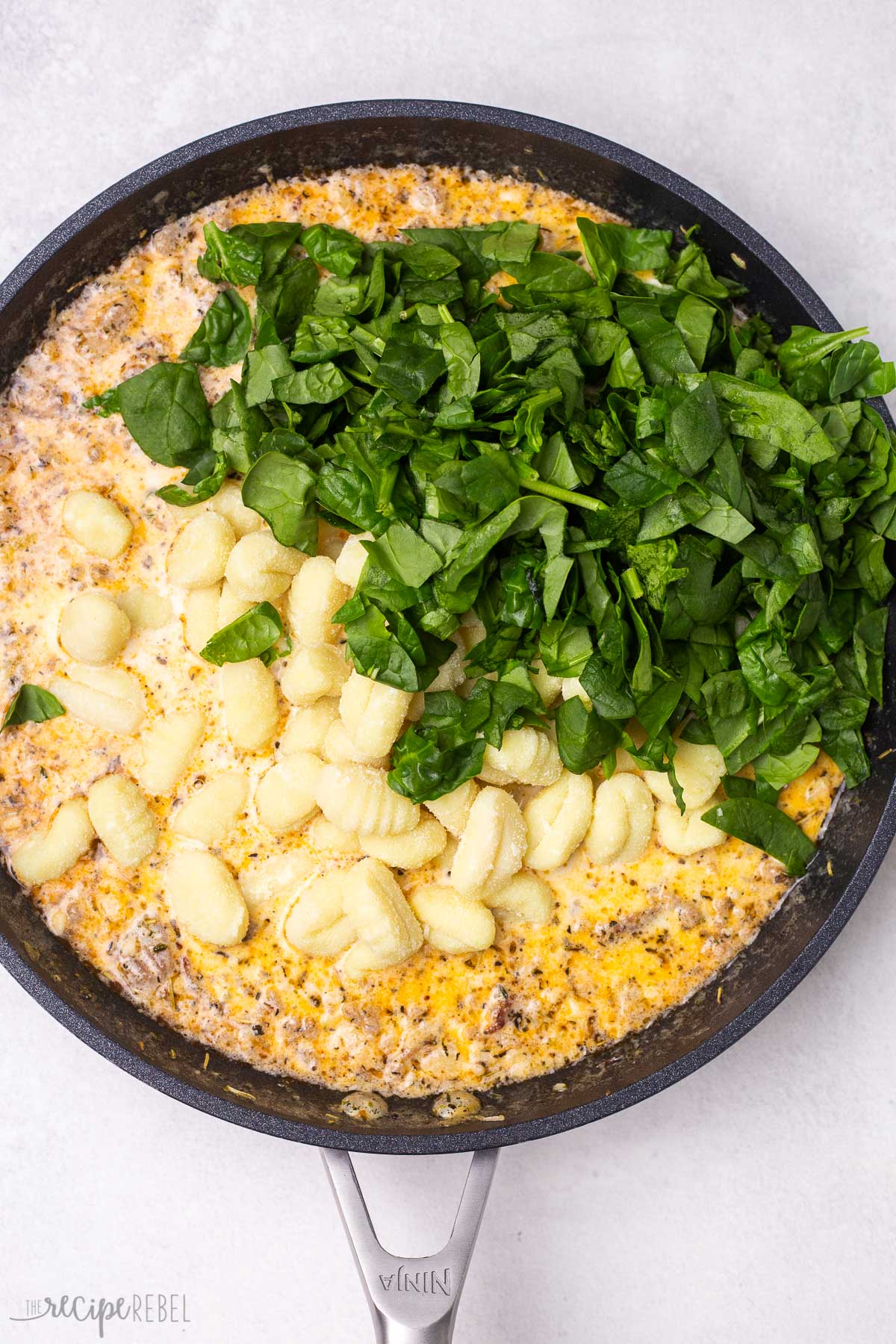 dried gnocchi and fresh spinach added to sauce in skillet.