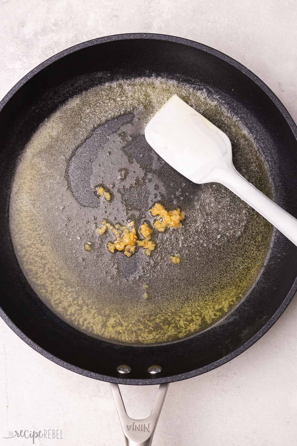 garlic cooking in melted butter in skillet.