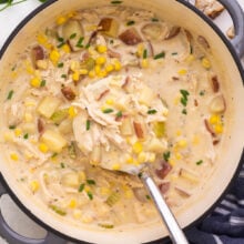 metal ladle scooping chicken corn chowder from large grey pot.