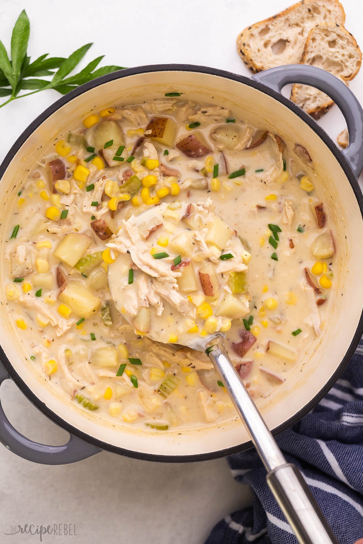 metal ladle scooping chicken corn chowder from large grey pot.