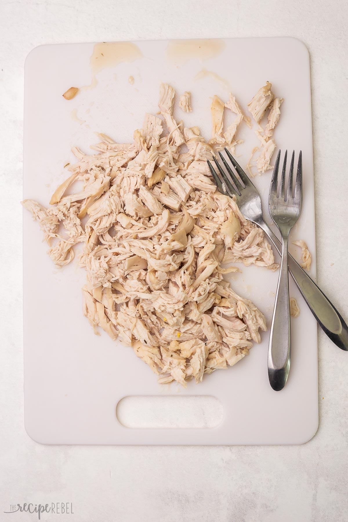 shredded chicken on white cutting board.