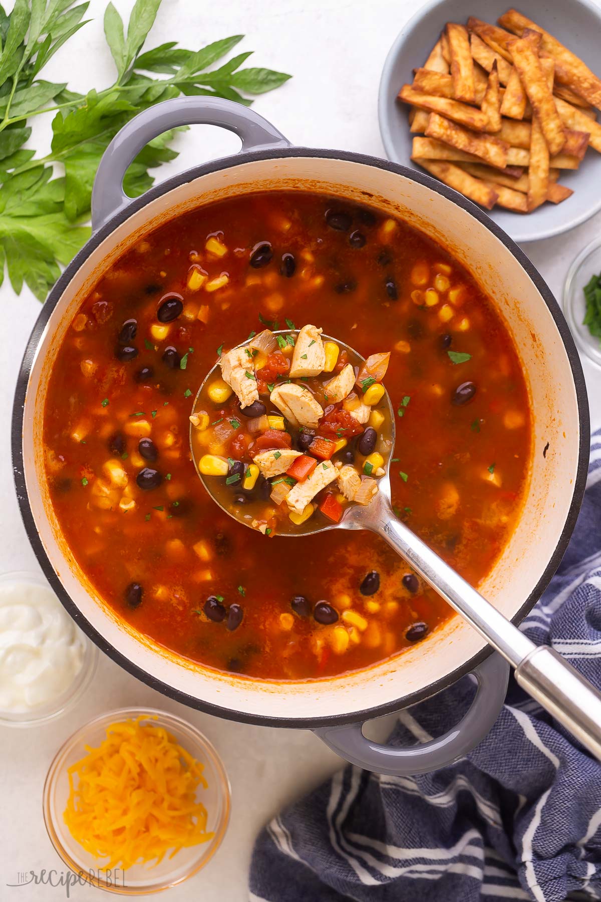 metal ladle scooping chicken tortilla soup from large dutch oven.