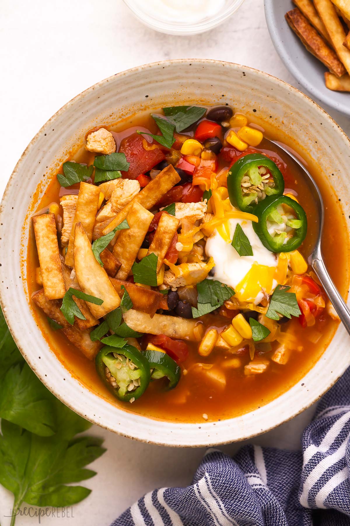 close up image of a bowl of chicken tortilla soup with spoon stuck in.