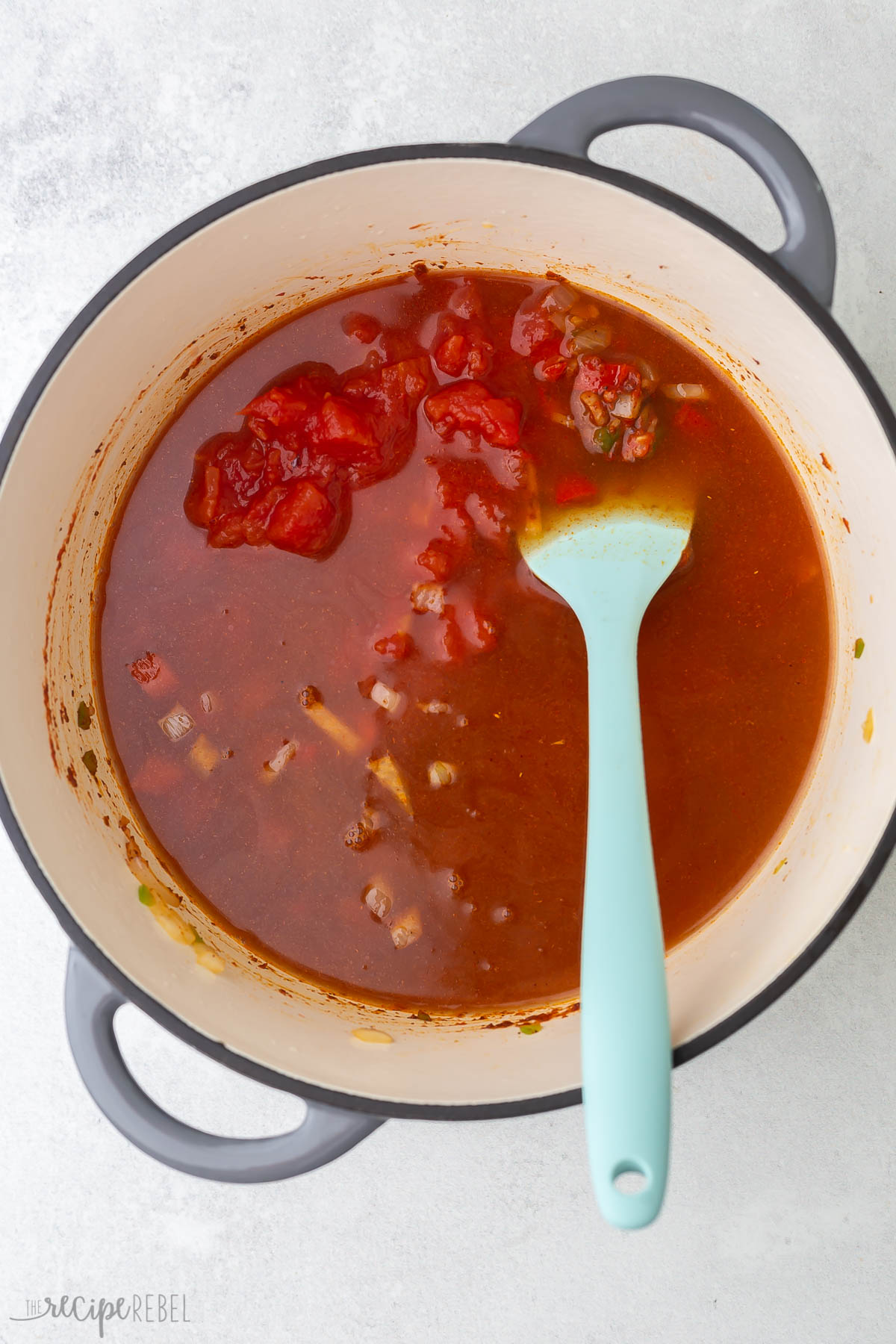 liquid and tomatoes added to vegetables in soup pot.