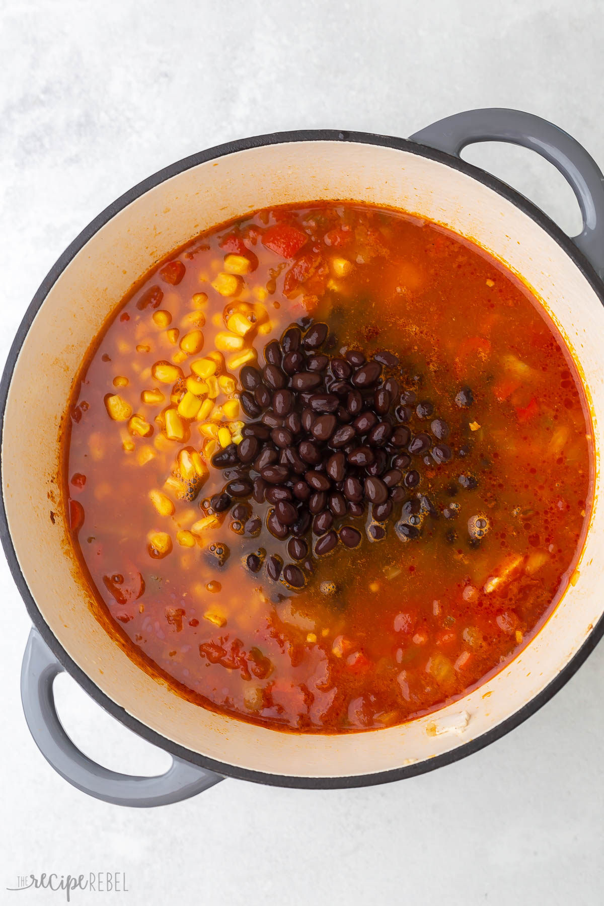 beans and corn added to tortilla soup in large pot.