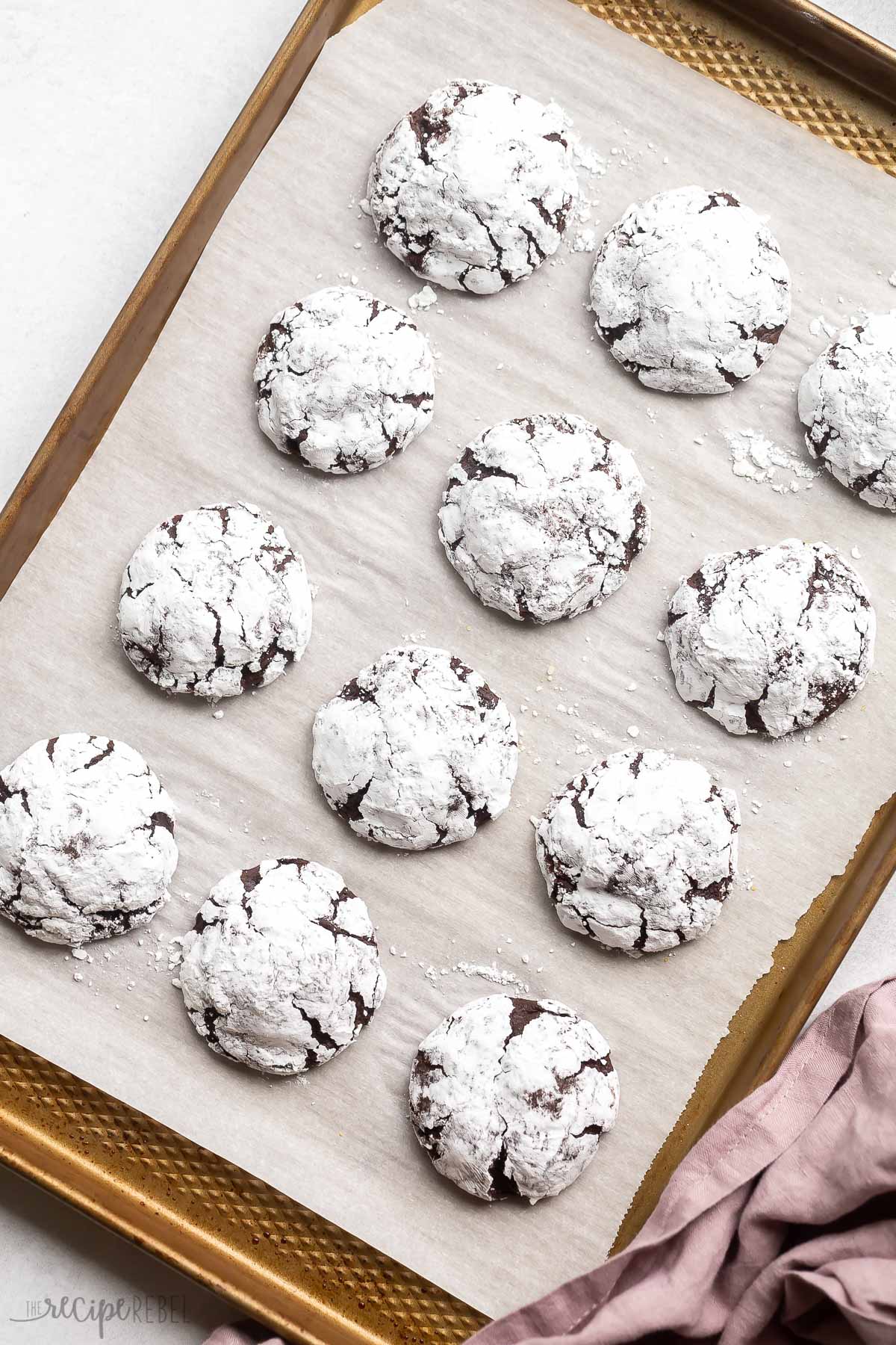 chocolate crinkle cookies on a baking sheet with parchment paper.