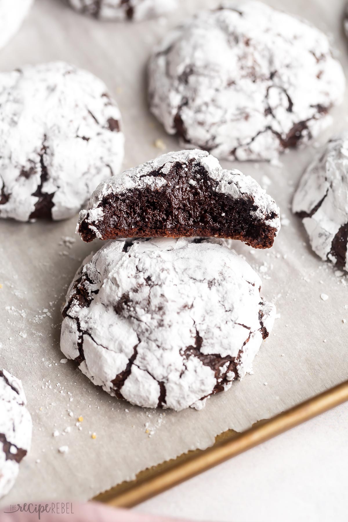 one half eaten chocolate crinkle cookie stacked on another.