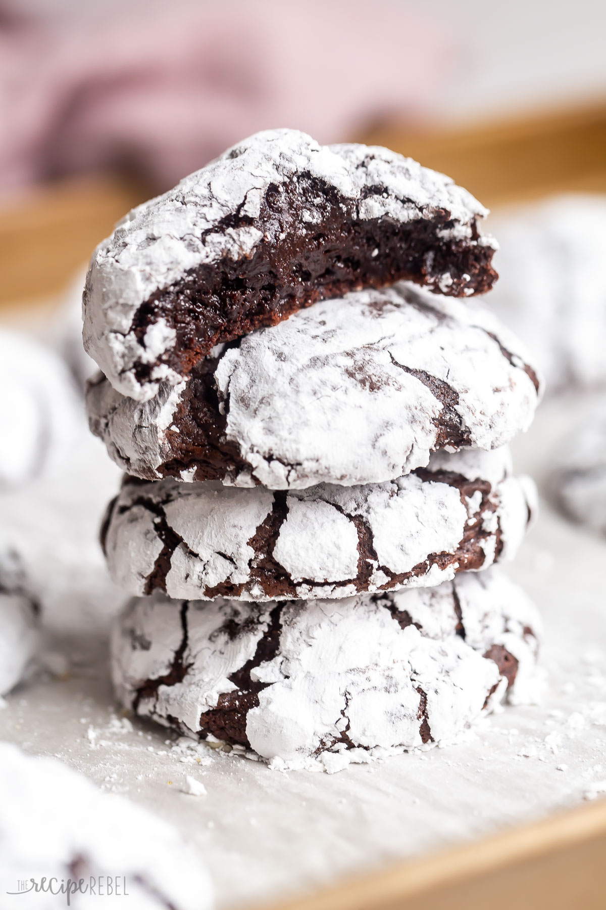 stack of chocolate crinkle cookies with more in the background.