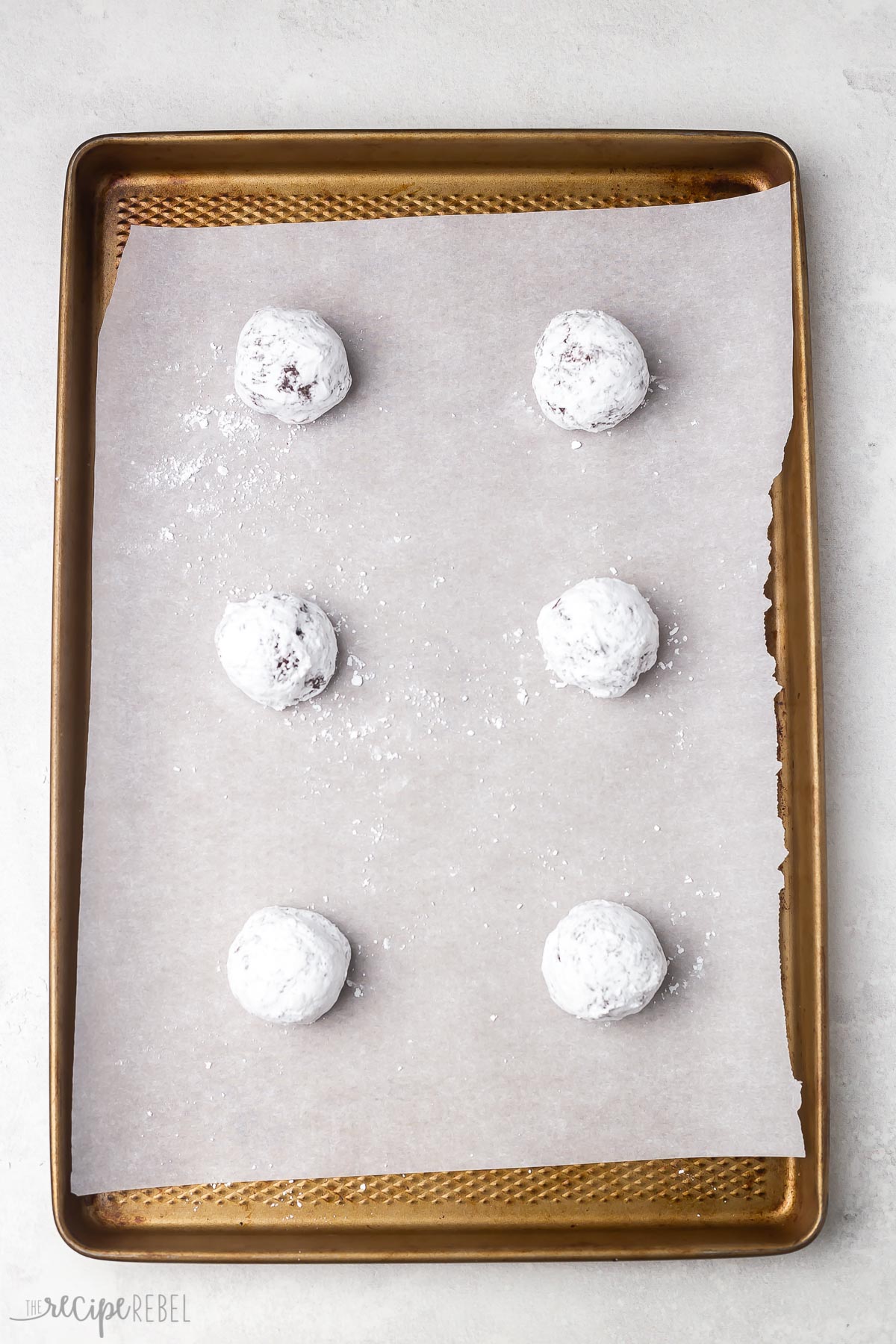 powdered sugar coated cookies on parchment lined baking sheet.