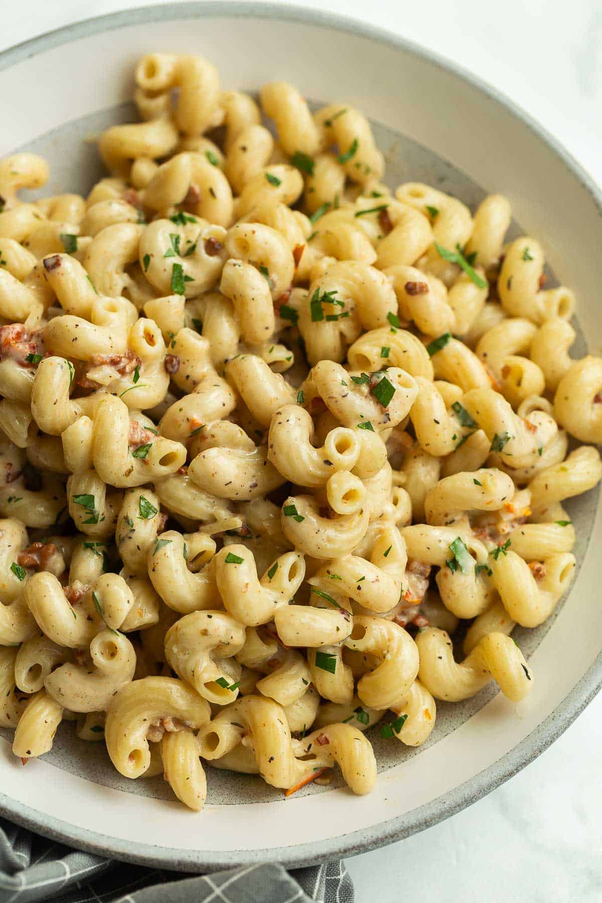 close up image of cavatappi pasta in grey bowl with fresh parsley.