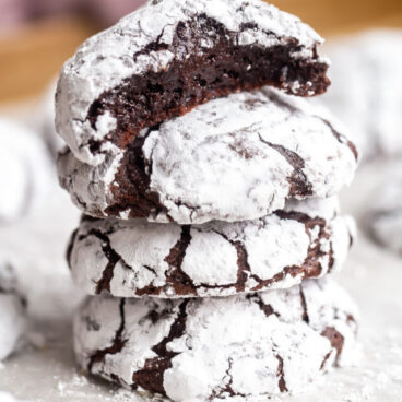 stack of chocolate crinkle cookies with more in the background.